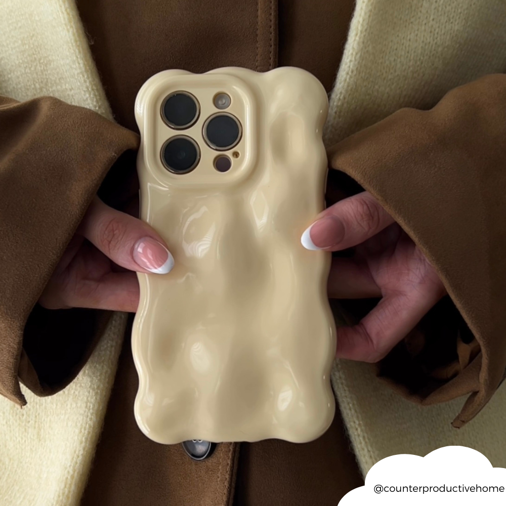 Butter yellow 3D bubble phone case held in hands; person wears a brown and cream coat.