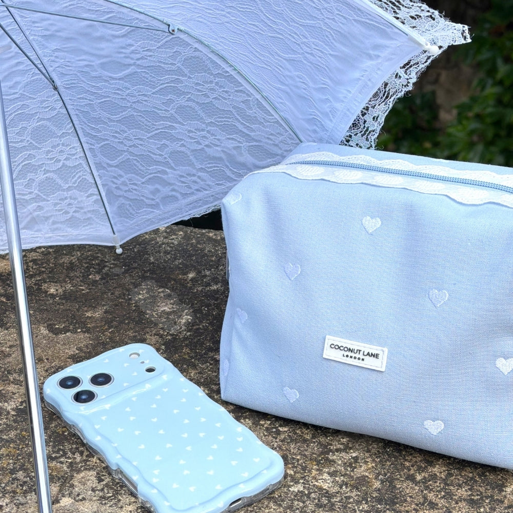 white lace umberlla next to Powder Blue Hearts Makeup bag and Phone Case
