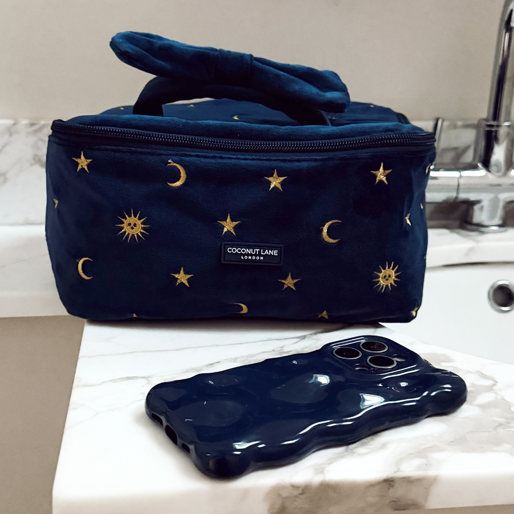Navy makeup bag with sun and moon pattern next to a navy 3D bubble phone case.