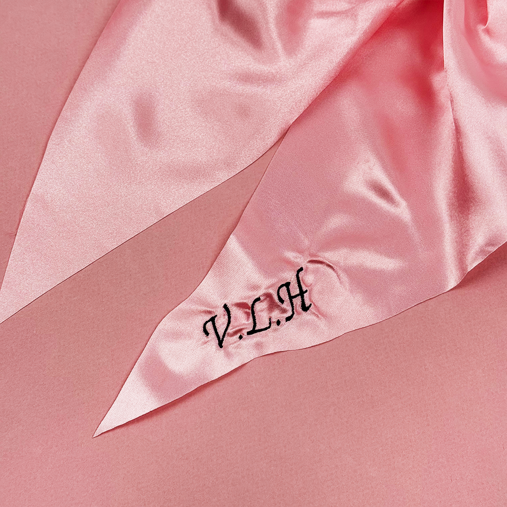 Pink satin fabric with 'V.L.A' monogram on a pink background