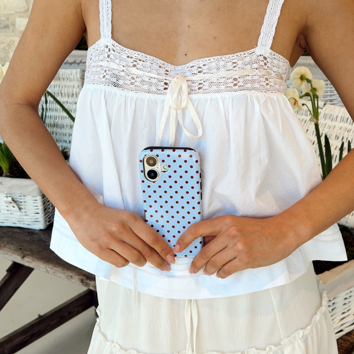 Girl in spring top holding her brown and blue polka dot phone case