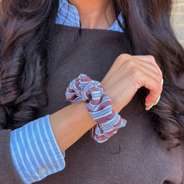 Girl wearing blue and brown scrunchie on her wrist in a matching outfit