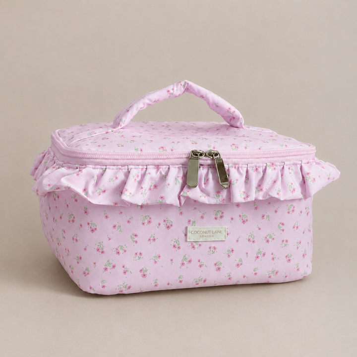 Pink floral patterned Vanity Bag with ruffled trim, handle and zip closure.