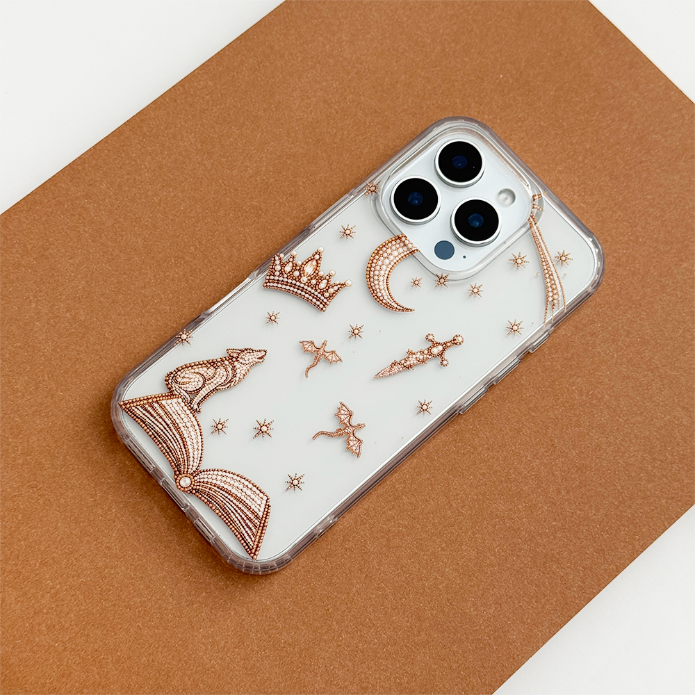 Fantasy Girl Clear Phone Case featuring rose gold illustrations of a crescent moon, crown, dagger, dragons, wolf and open book, photographed diagonally on a warm brown background.