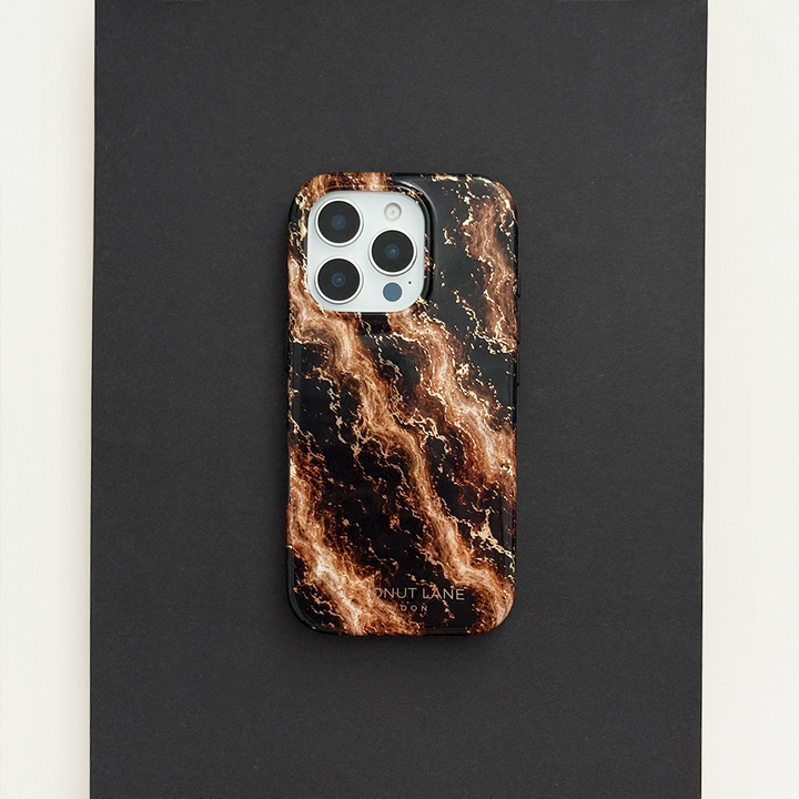 Black phone case with a swirling bronze and gold marble pattern, on a phone with three camera lenses, resting on a black surface.