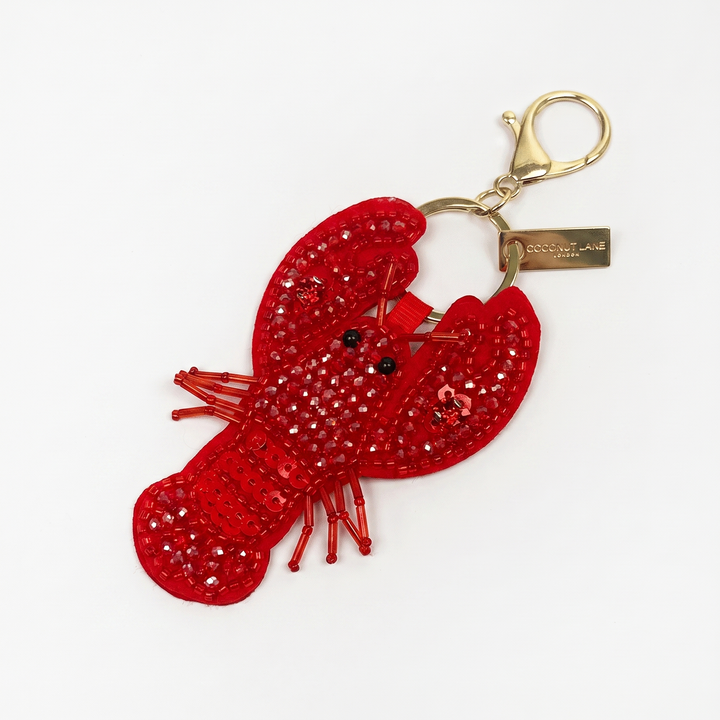 A beaded red lobster-shaped keyring, featuring a gold-tone lobster clasp, set against a plain white background.