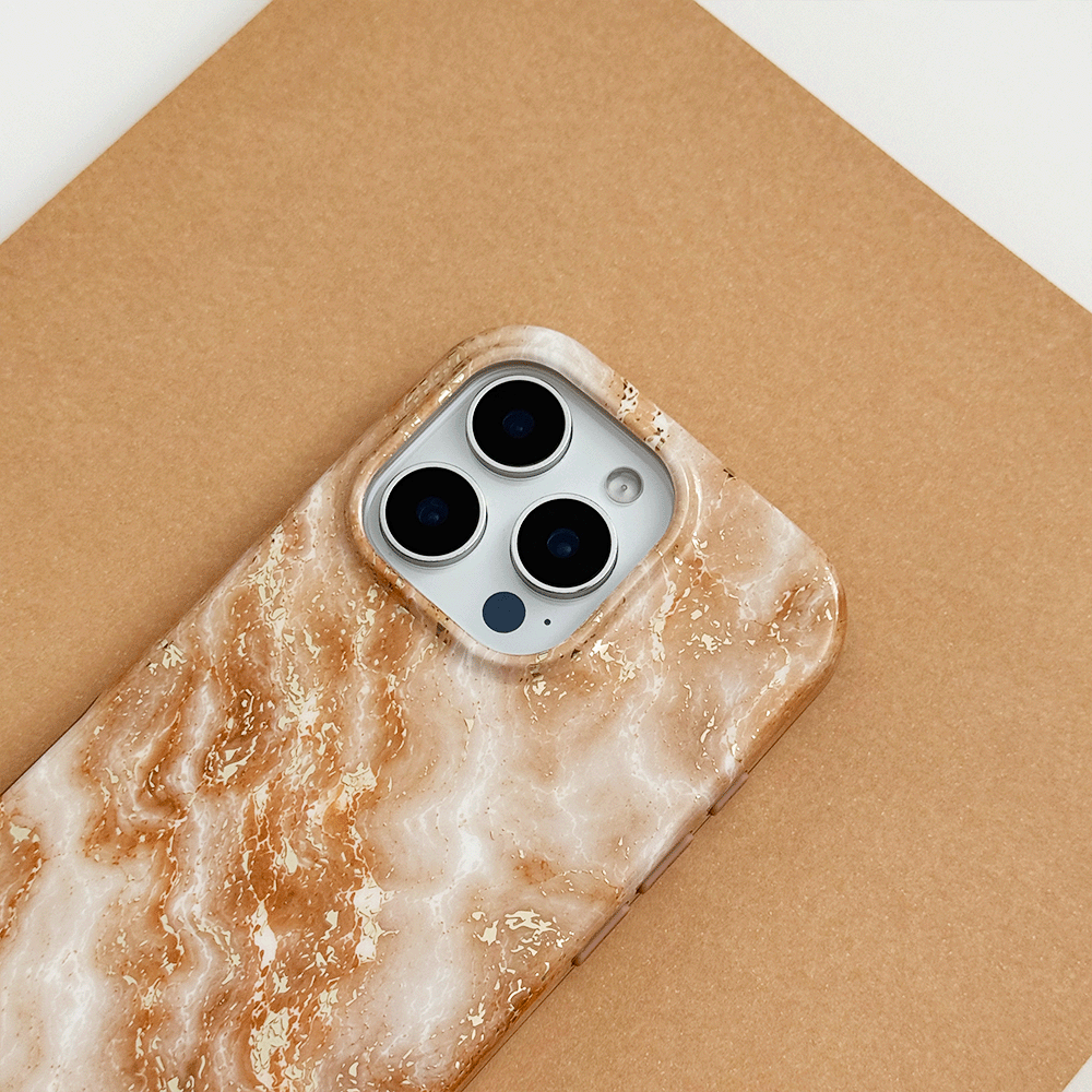Cream and caramel marble phone case with gold veining, on a phone with three camera lenses, resting on a tan surface.