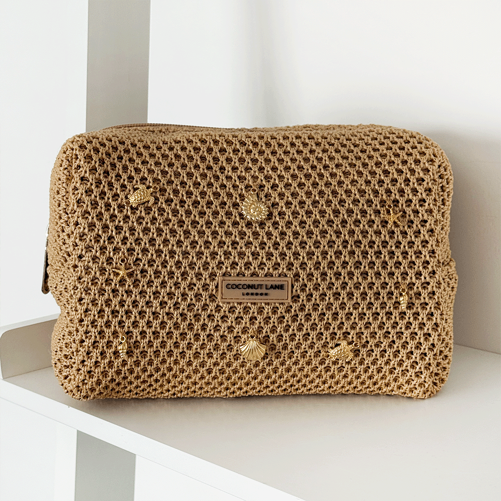 Brown woven makeup bag with gold charms attached.