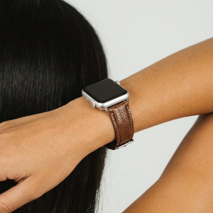 Chocolate brown textured vegan leather Apple Watch strap on wrist, hand raised near face.
