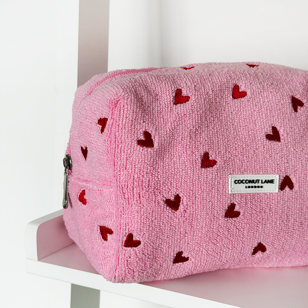 Pink pouch with red heart patterns on a white surface