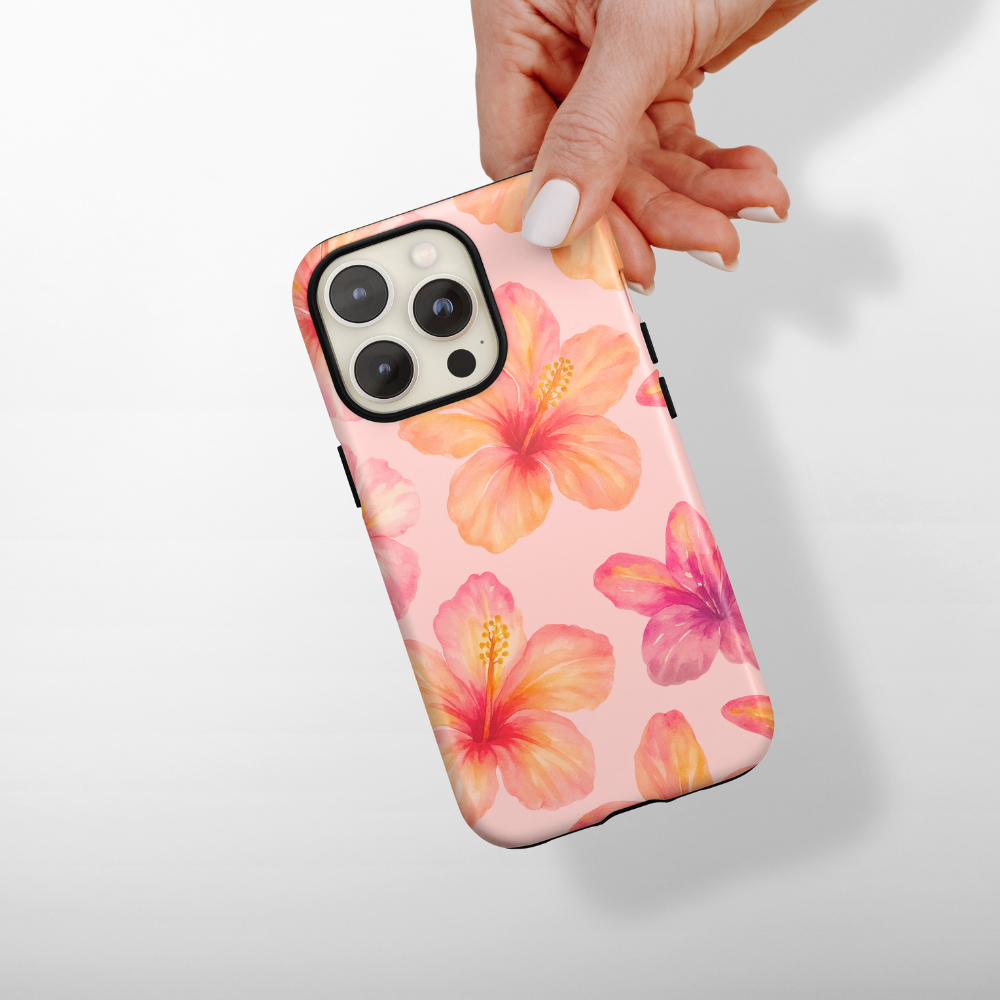 Hand holds a pink phone case with bold hibiscus flower pattern.