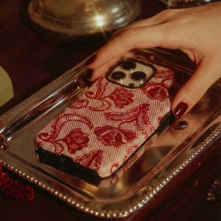 Red Lace Tough Phone Case laying on a silver platter on a brown vanity desk