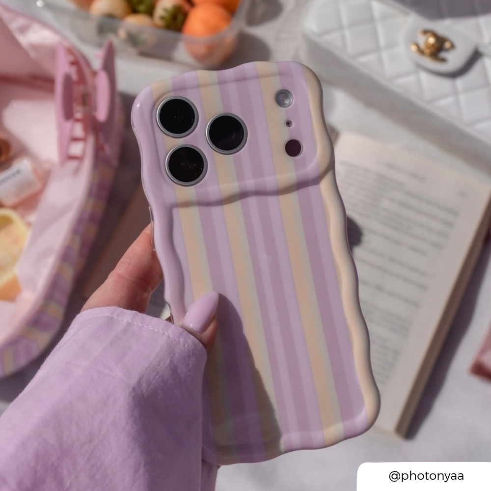 Phone case with striped design held by a hand, with a blurred background