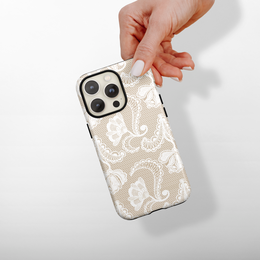 Coconut Lane Tough Phone Case in ivory with a white floral lace pattern, shown held in one hand.