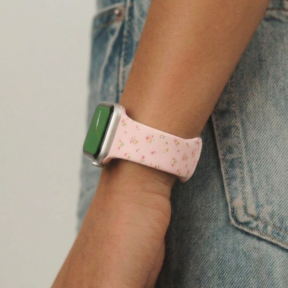 Coconut Lane pink floral Apple Watch strap on wrist, shown next to light blue denim jeans.