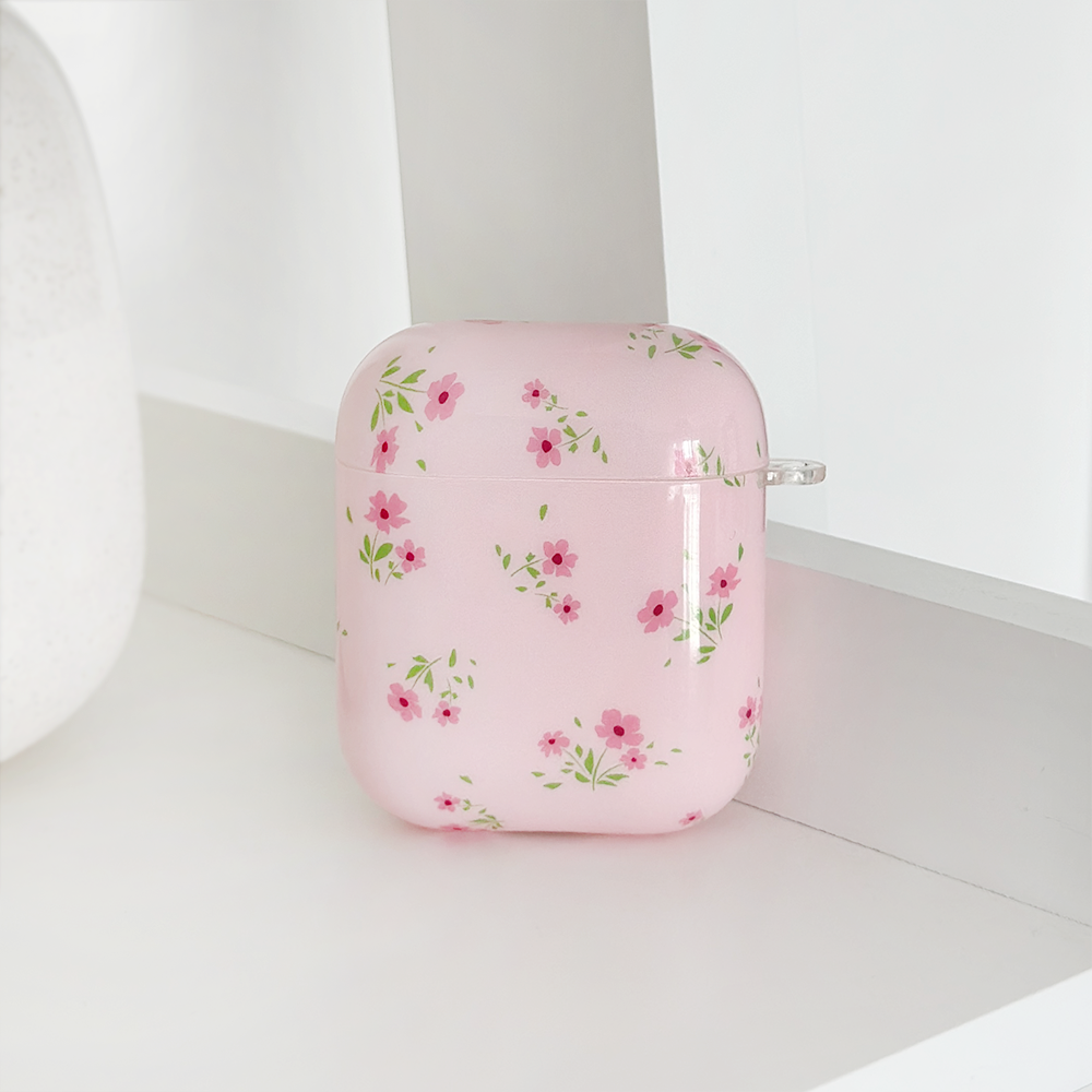 The AirPods Case - Ditsy Floral Pink by Coconut Lane features a delicate pattern of small pink flowers and green leaves displayed against a white background. This sleek, glossy case showcases the intricate design beautifully through IMD Print Technology.