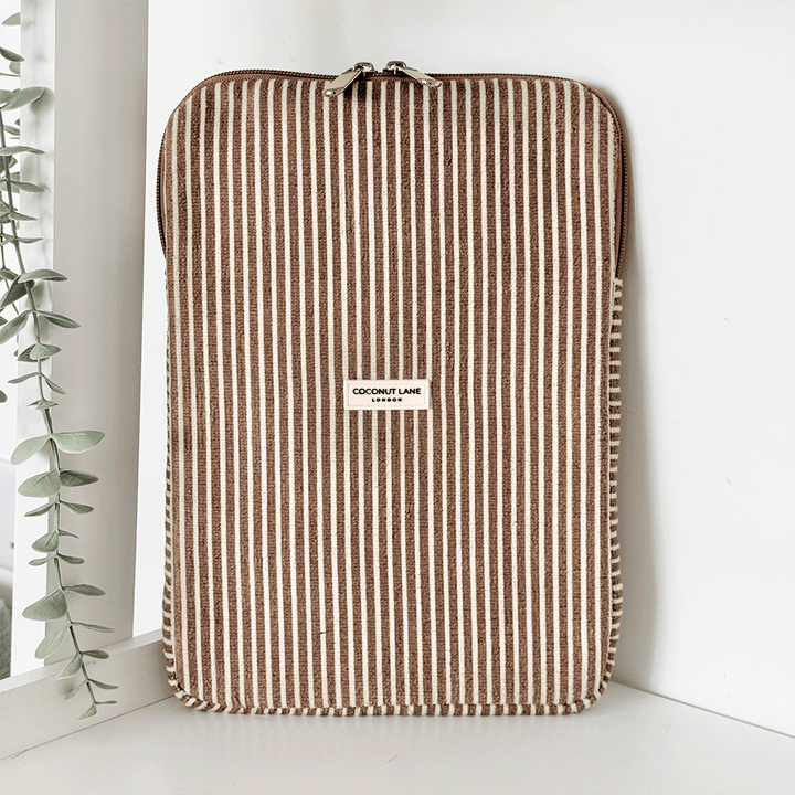 Chestnut striped iPad sleeve by Coconut Lane, with towel-like texture, displayed near a plant on a white shelf.