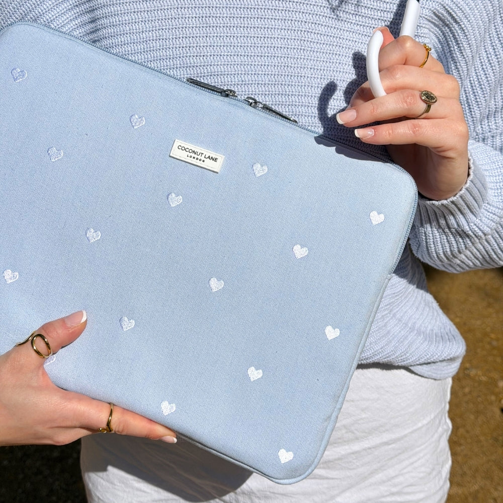 Light blue linen laptop sleeve with white heart patterns held by a person wearing a light blue jumper.